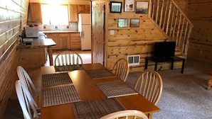 A wooden cabin interior with a dining table, chairs, a kitchen area, and a staircase. - Balcony, 20 min to Yellowstone, Sled/ATV Spot (Island Park)