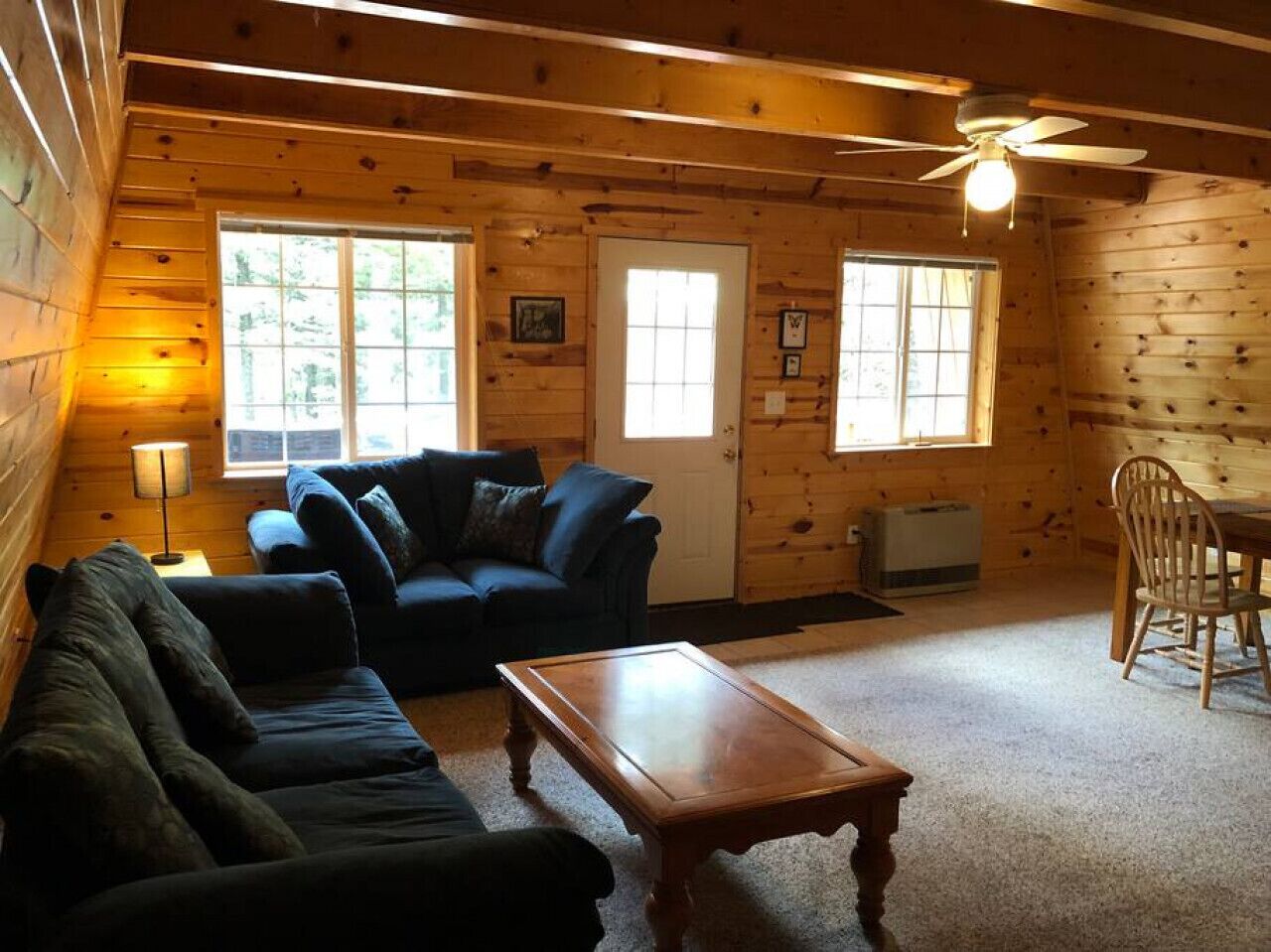 Un intérieur de chalet chaleureux, avec un revêtement mural en bois, un canapé, une table basse et un coin repas.