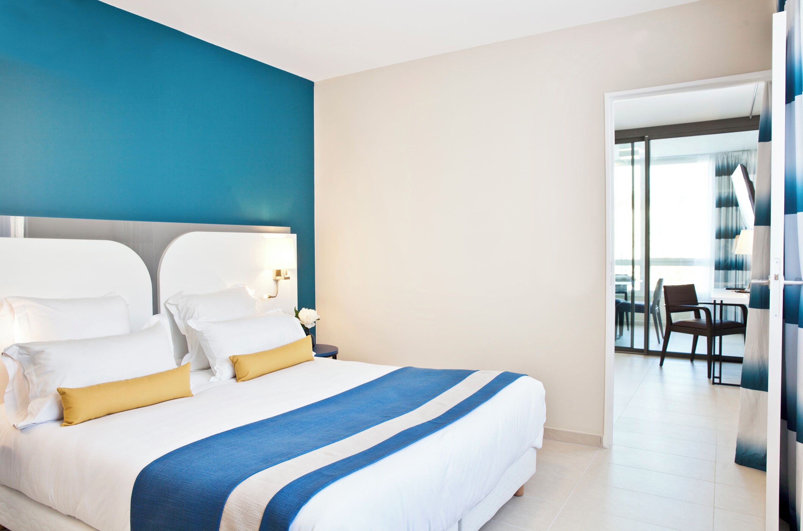 A hotel room with a large bed, a nightstand, a desk, and a view of the room's interior.