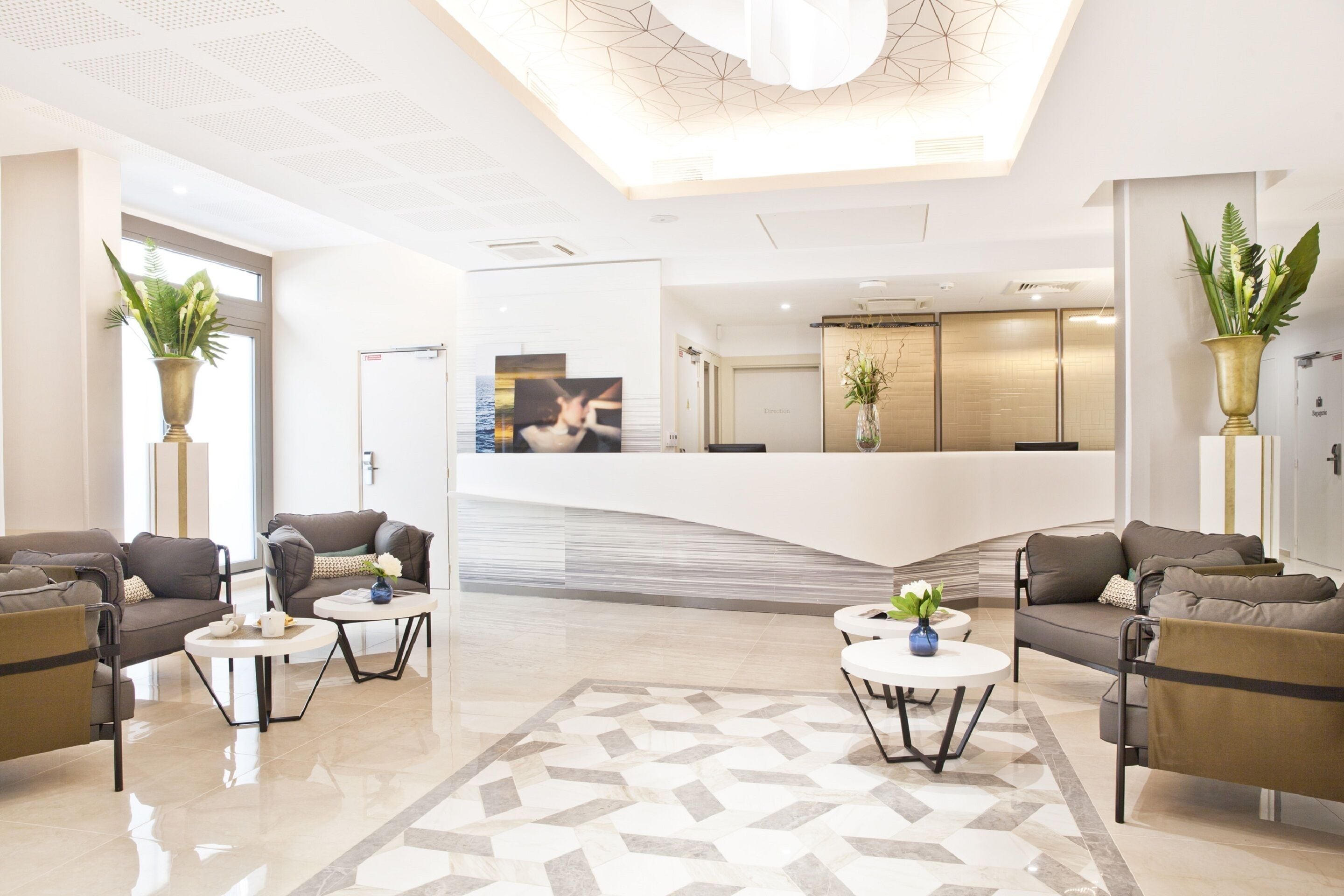 Een moderne hotel lobby met banken, salontafels en potplanten.