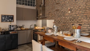 Une cuisine avec un mur en briques, une table en bois et divers appareils de cuisine.