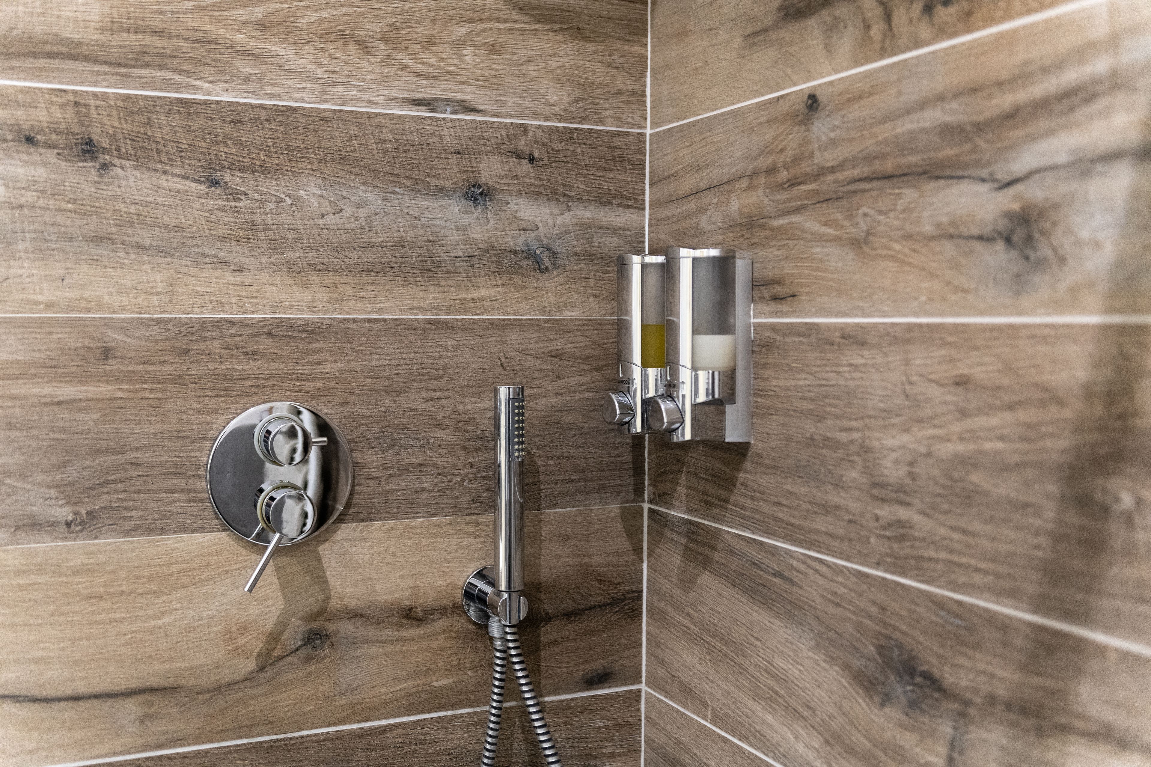 A shower area with wooden paneling and a modern chrome showerhead.