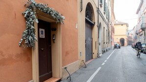 Une rue étroite bordée d’un immeuble dont la porte est d’un brun foncé et sur lequel on peut voir une enseigne indiquant qu’il s’agit d’une maison d’hôtes.