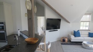 Et moderne køkken med en træskål på bordet, en indbygget ovn og et stort spejl.