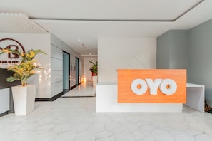 Un espace d’accueil avec une enseigne indiquant « OYO » et un logo pour « ONE BLANC APARTMENTS ».