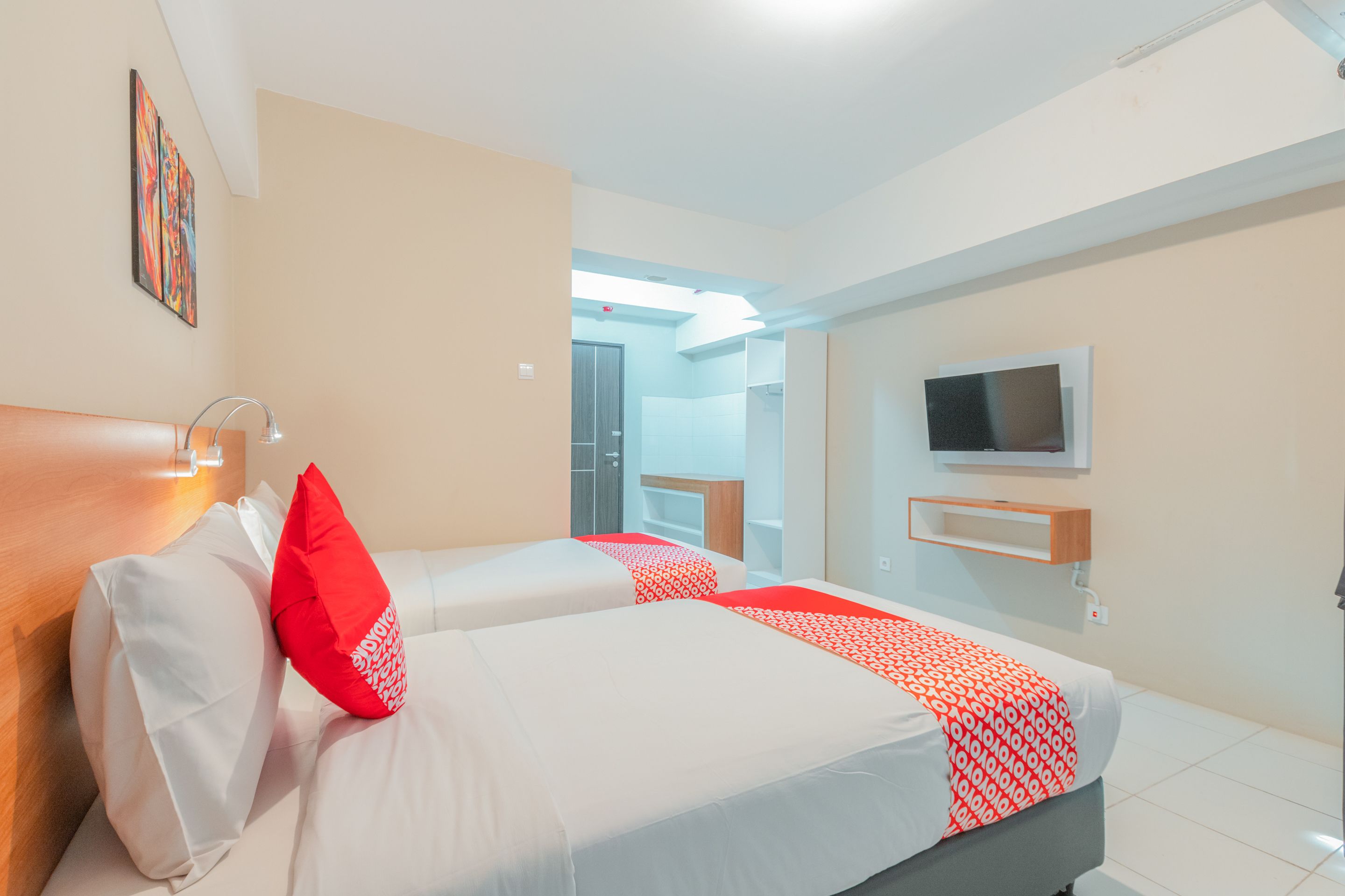 Une chambre d’hôtel avec deux lits, un téléviseur fixé au mur et une salle de bain visible à travers une porte ouverte.