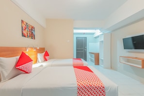 Une chambre d’hôtel avec deux lits, une literie rouge et blanche, une télévision et des œuvres d’art accrochées au mur.