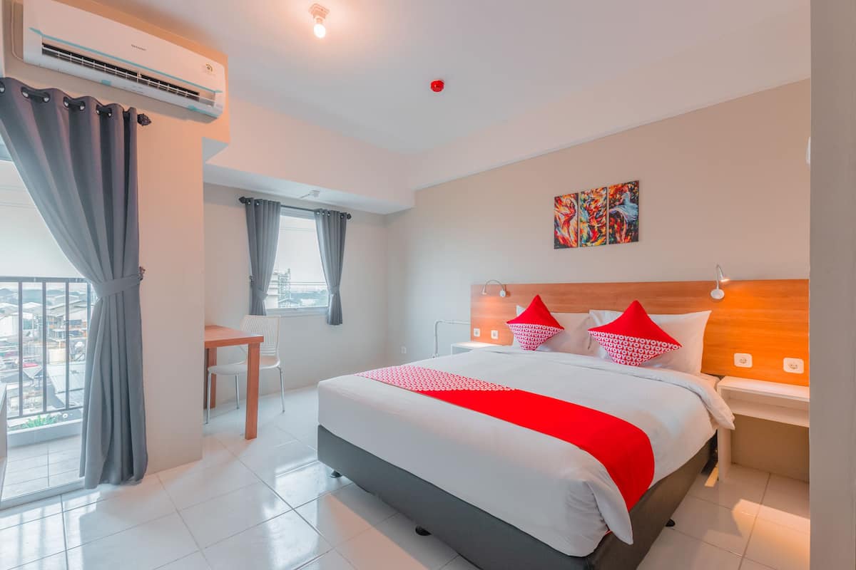 Ein modernes Hotelzimmer mit einem großen Bett, einem Schreibtisch und einem Balkon mit Vorhängen.
