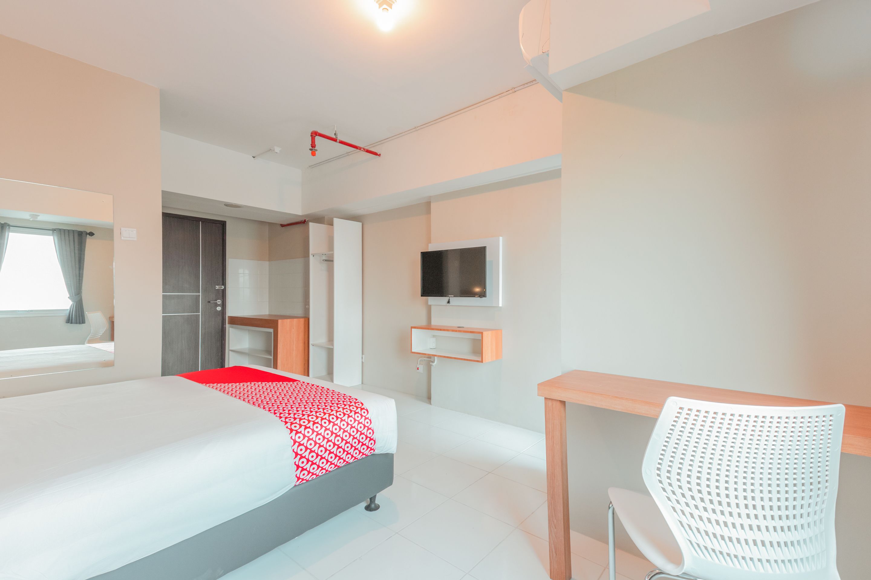 A hotel room with a bed, a desk, a chair, a TV, and a wardrobe.