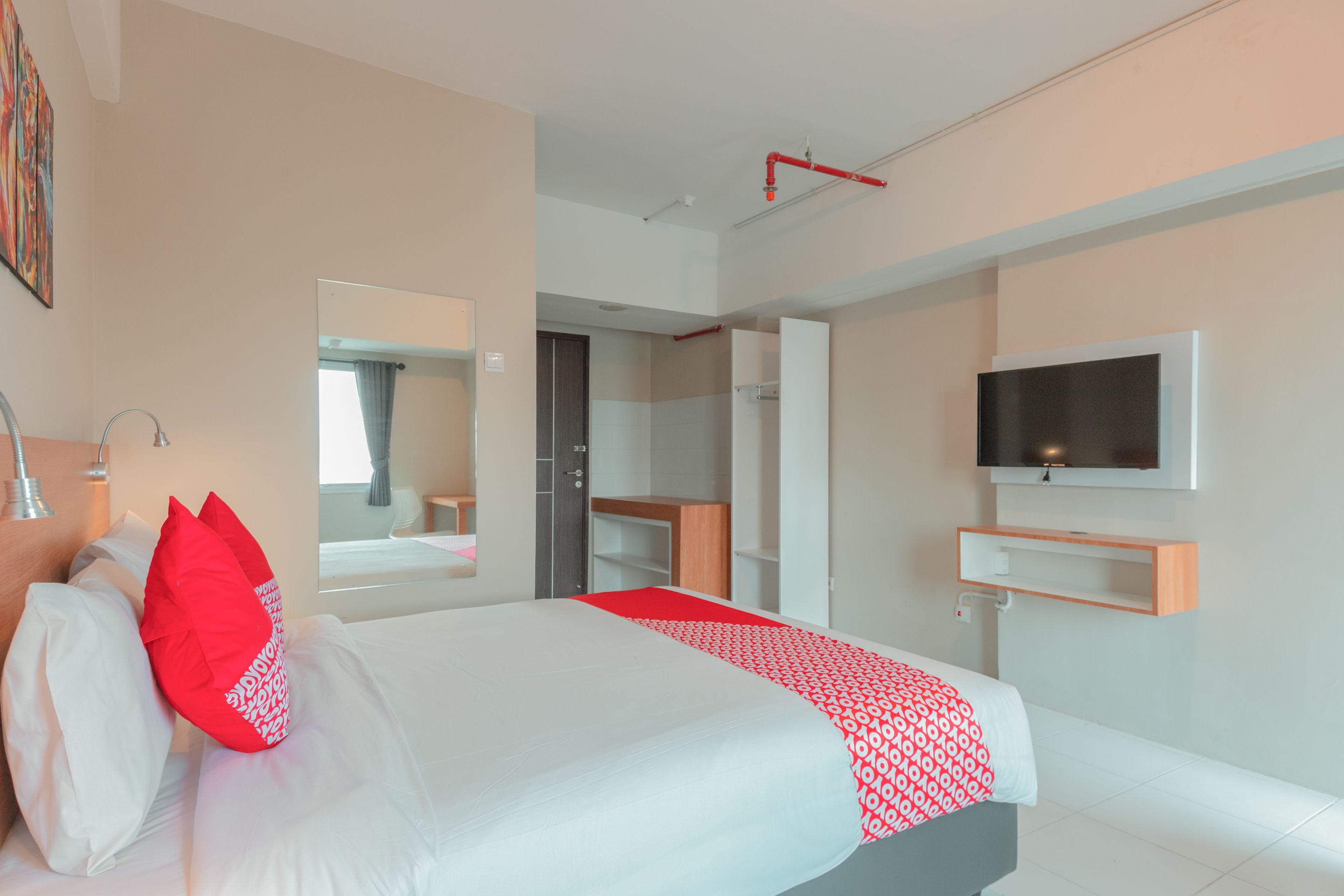 A modern hotel room with a large bed, a TV mounted on the wall, and a walk-in closet.