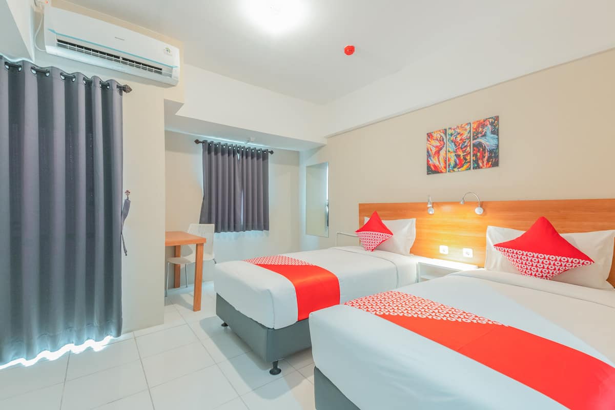 Ein Hotelzimmer mit zwei Betten, einem Schreibtisch und einer Klimaanlage.