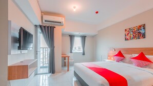 Une chambre d’hôtel moderne dotée d’un grand lit, d’un téléviseur à écran plat fixé au mur, d’un bureau et d’une fenêtre avec des rideaux.