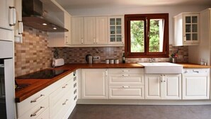 Una cocina con armarios blancos, encimera de madera, una ventana y un salpicadero de azulejos.
