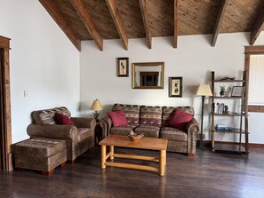 A living room with a wooden ceiling, two sofas with patterned cushions, a wooden coffee table, and a bookshelf. - 2BR, 1B, Sleeps 4, Lakeview and Lake access in West Glacier (West Glacier)
