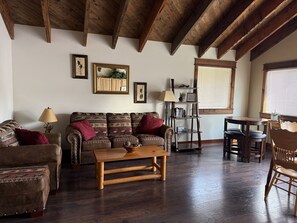 A living room with a wooden ceiling, a sofa, a coffee table, and a bookshelf. - 2BR, 1B, Sleeps 4, Lakeview and Lake access in West Glacier (West Glacier)