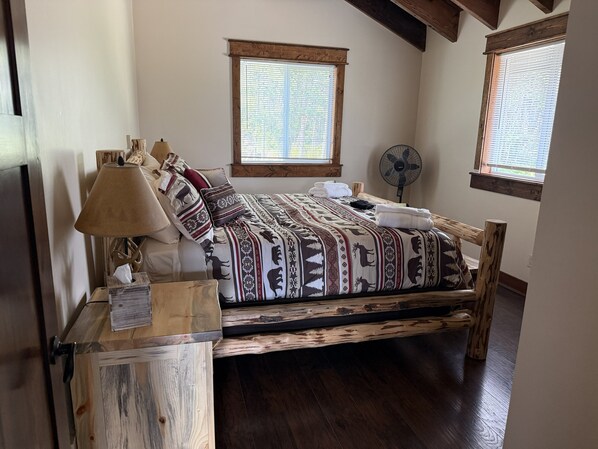 A wooden bed with patterned bedding, a bedside lamp, and a wooden nightstand. - 2BR, 1B, Sleeps 4, Lakeview and Lake access in West Glacier (West Glacier)
