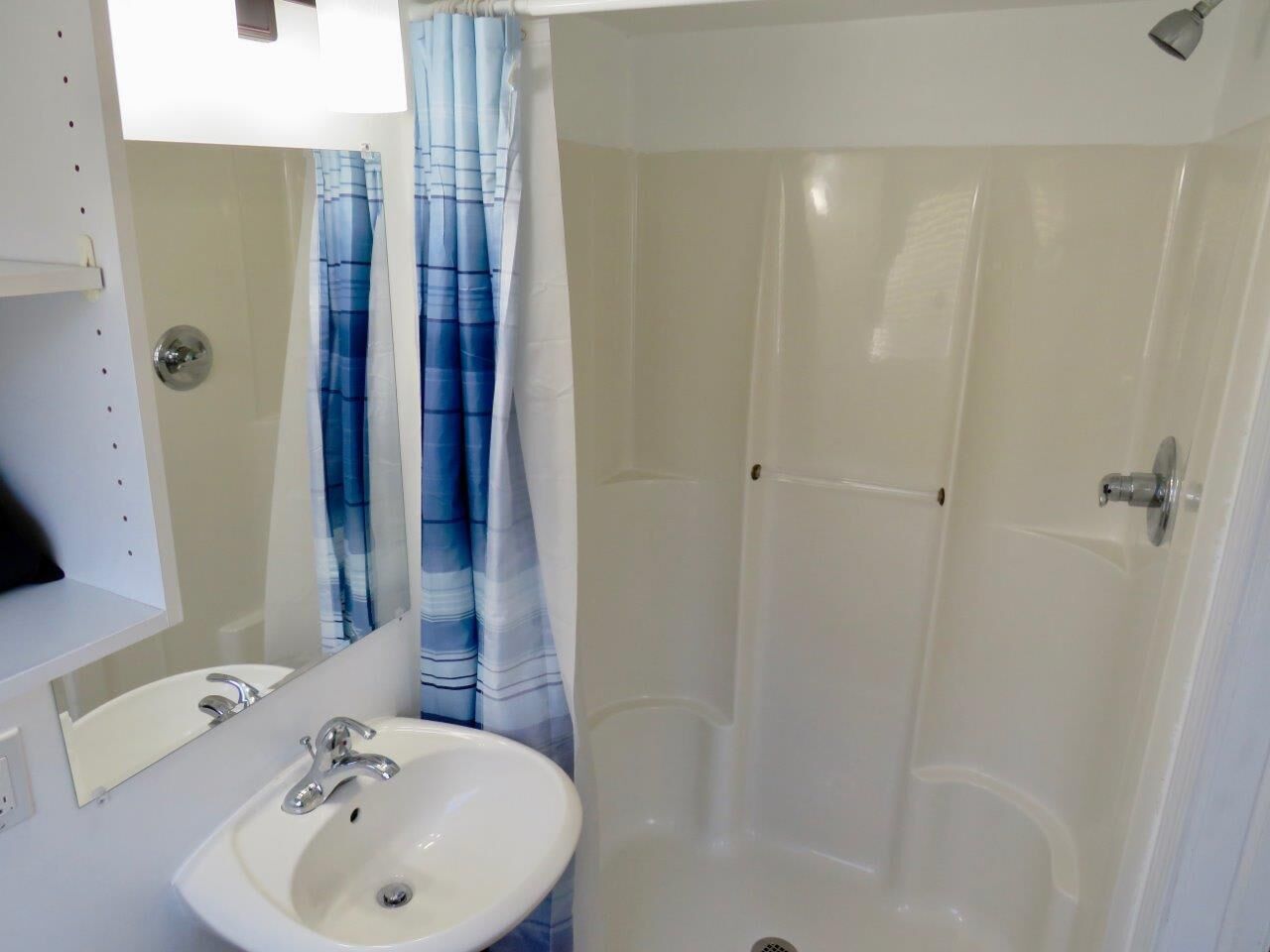 Een badkamer met een wastafel, spiegel en douche.