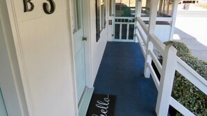 A hotel entrance with a blue carpet, a white porch railing, and a door marked with the number B3.