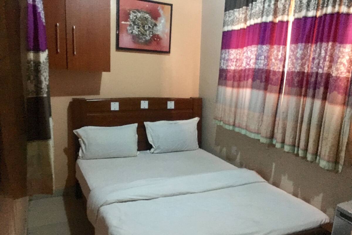 Una cama individual con cabecera de madera, dos almohadas y una colcha blanca sencilla.