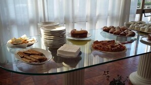 Ein Buffet mit verschiedenen Speisen, darunter Gebäck und Brot, sowie gestapelten Tellern.