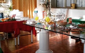 Un comedor con una mesa de vidrio, mantel rojo y diversos alimentos.