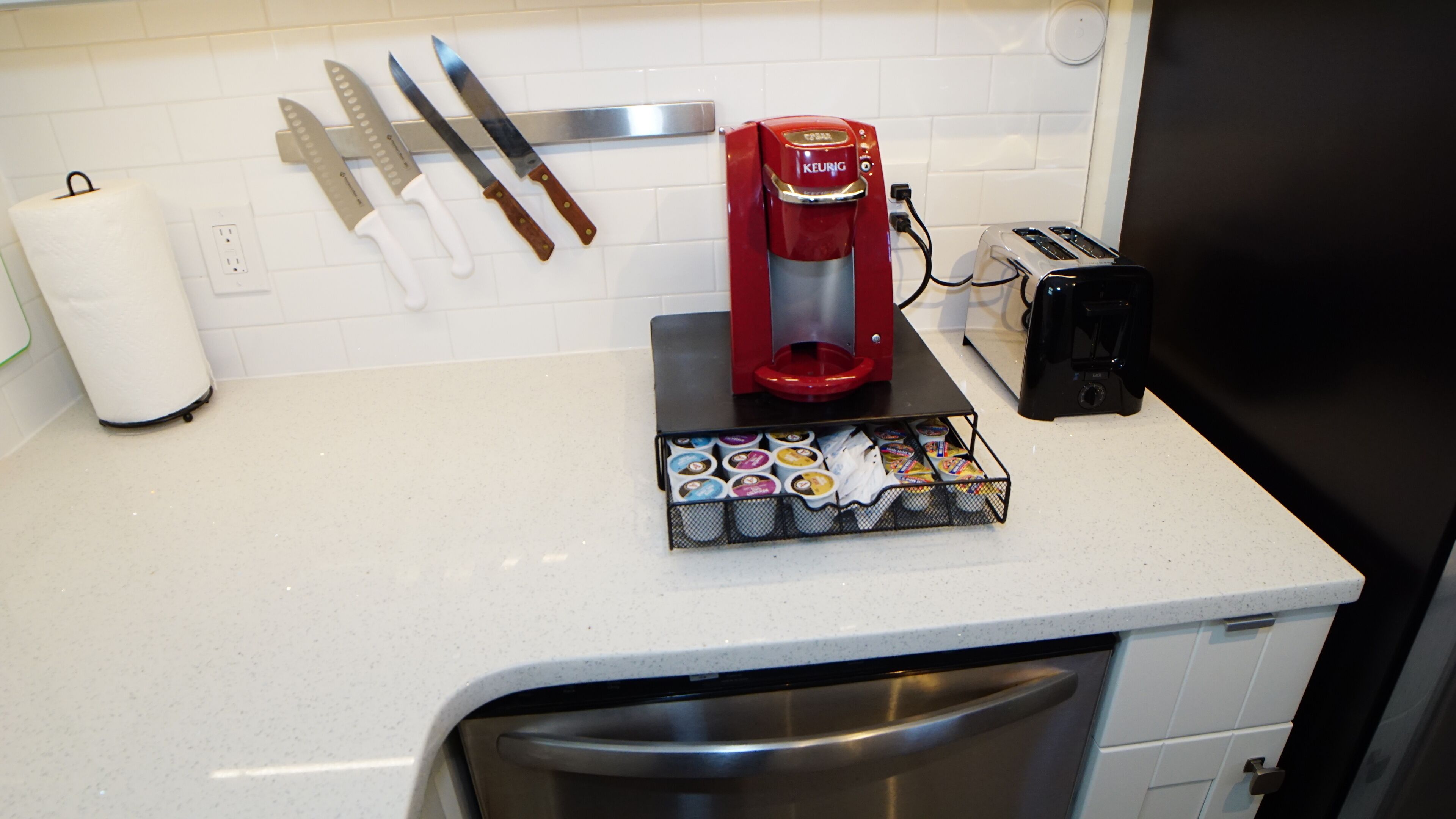 Eine Küche mit Kaffeemaschine, Toaster und einer Kapselbox für Kaffee.