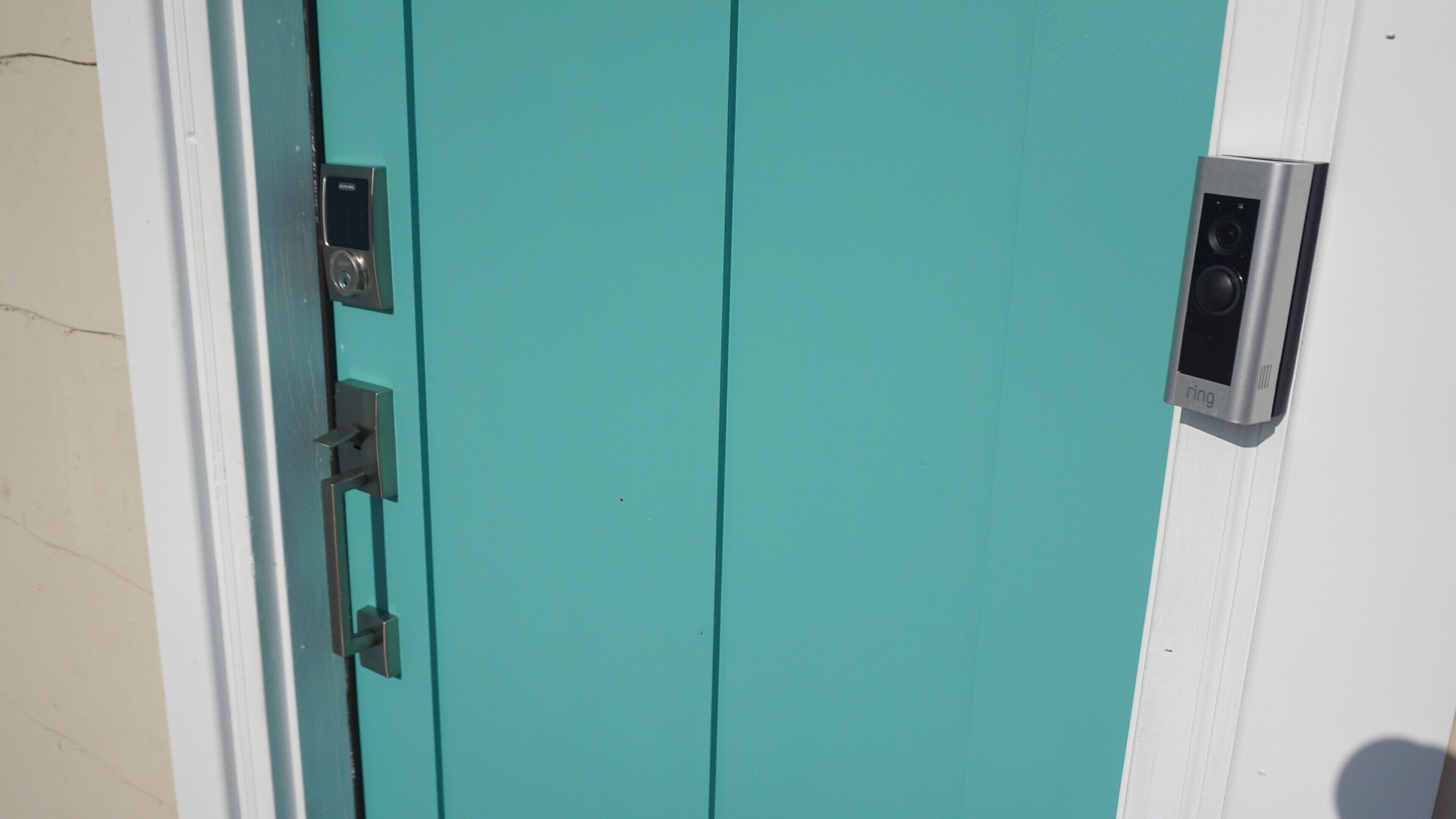 A teal door with a doorbell and a door lock.