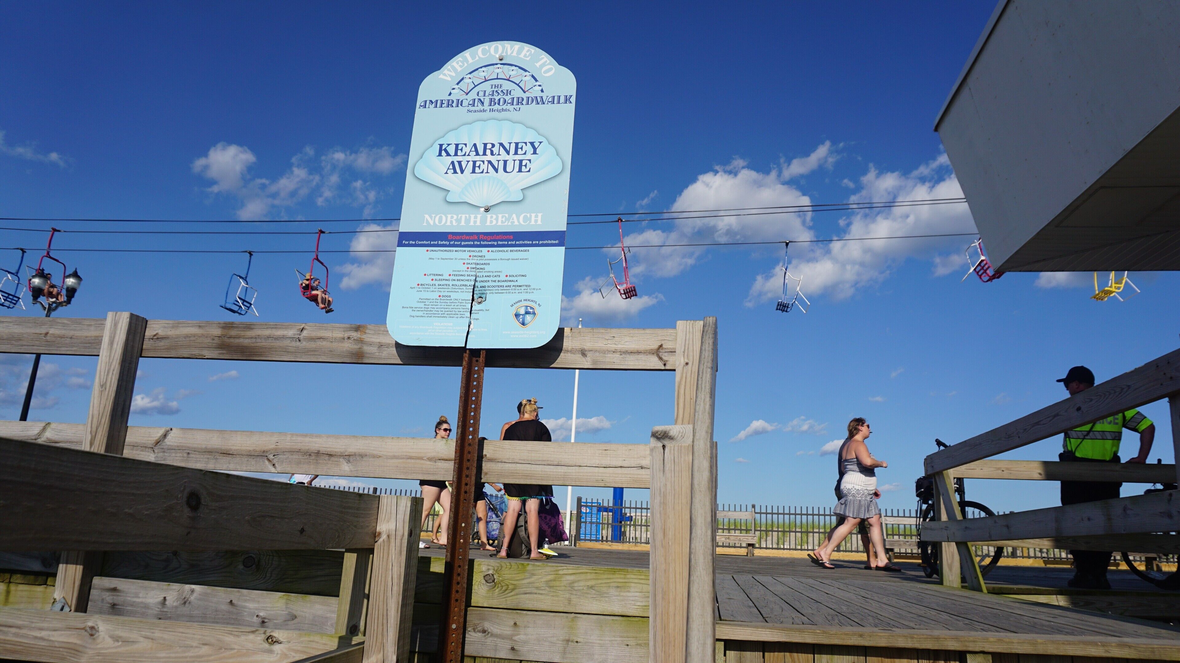 A wooden boardwalk with a sign indicating it's the American Classic Boardwalk in Seaside Heights, NJ.