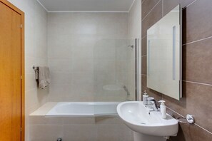 A modern bathroom with a bathtub, a sink, and a glass shower enclosure. - Centric and Spacious Apartment With Wifi and Balcony (Gzira)