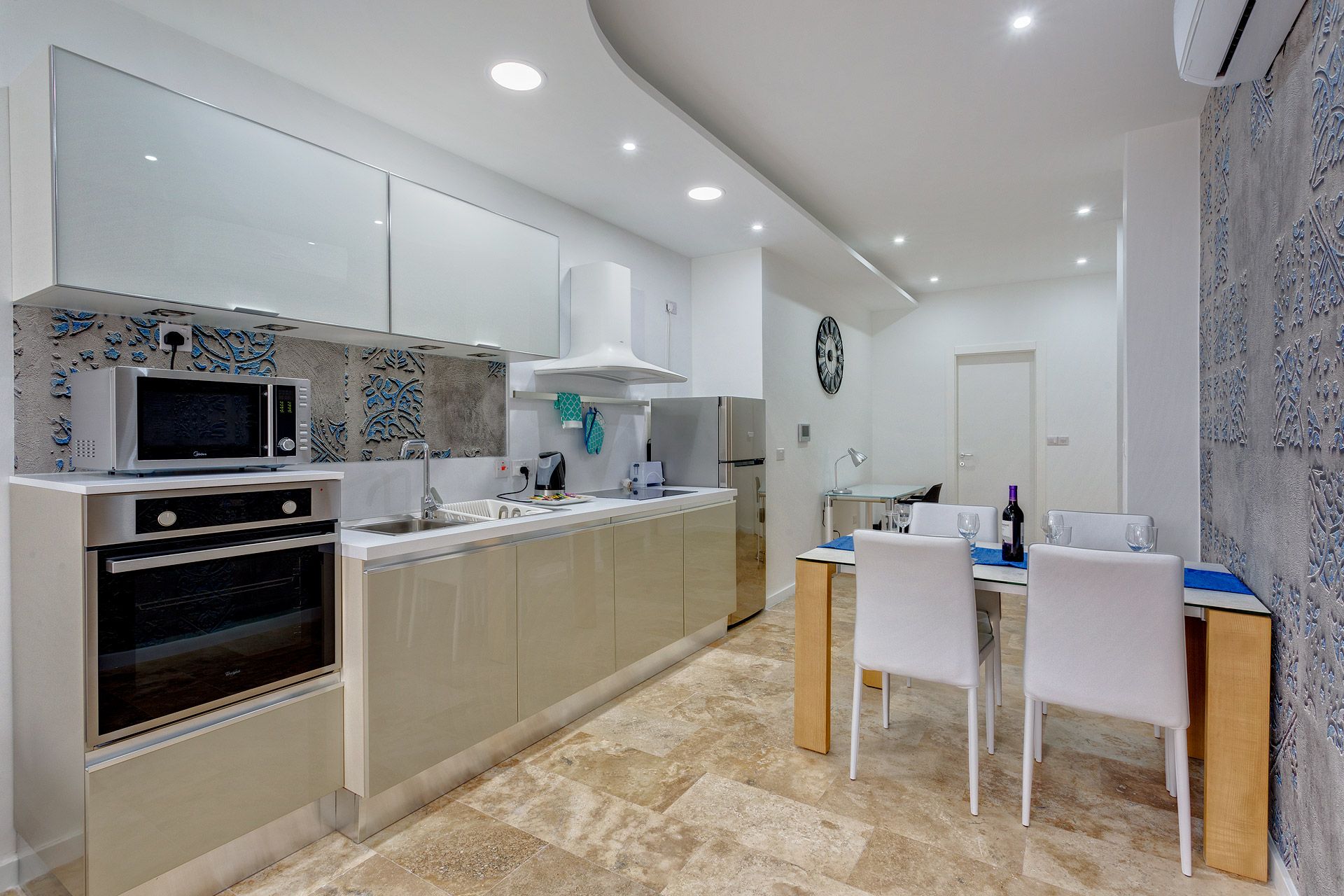 A modern kitchen with a microwave, oven, and sink. There is a dining area with a table and chairs.