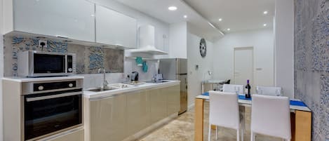 A modern kitchen with a microwave, oven, and sink. There is a dining area with a table and chairs.