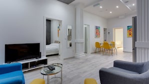 Uma sala de estar moderna com televisão de tela plana, uma mesa de centro de vidro e um sofá.