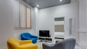 Uma sala de estar moderna com sofá, poltrona, televisão e cama.