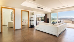 Ein modernes Wohnzimmer mit einem weißen Sofa, einem Flachbildfernseher und einem großen Fenster mit Blick auf die Stadt.