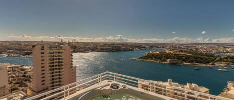 A high-rise hotel with a view of a coastal city, including a marina and a historic island fortress.