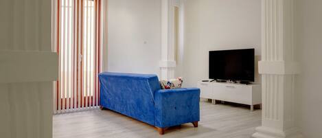 Una sala de estar moderna con un sofá azul, un televisor de pantalla plana y un mueble blanco.