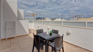 A rooftop terrace with a table and chairs, a view of the cityscape, and construction cranes in the distance. - Modern Penthouse in the Heart of Saint Julian's (St. Julian's)