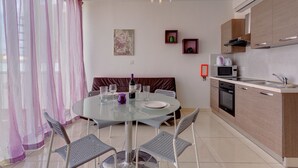 A modern kitchen with a microwave, oven, and sink. There is a dining area with a glass table and chairs. - Modern Penthouse in the Heart of Saint Julian's (St. Julian's)