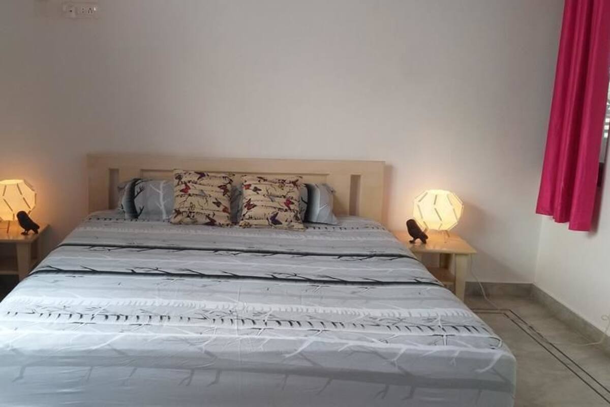 Une chambre à coucher avec un lit, deux tables de chevet, deux lampes et deux rideaux rouges.
