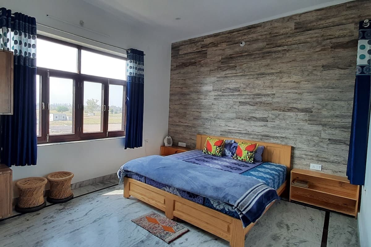 Une chambre à coucher avec un lit en bois, une armoire et une grande fenêtre avec des rideaux.