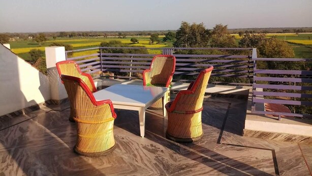 Una terrazza con sedie in vimini e un tavolo, affacciata su un paesaggio rurale.