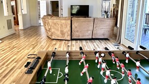 Amplia sala de estar con una mesa de fútbol, un televisor grande y una zona de estar acogedora.