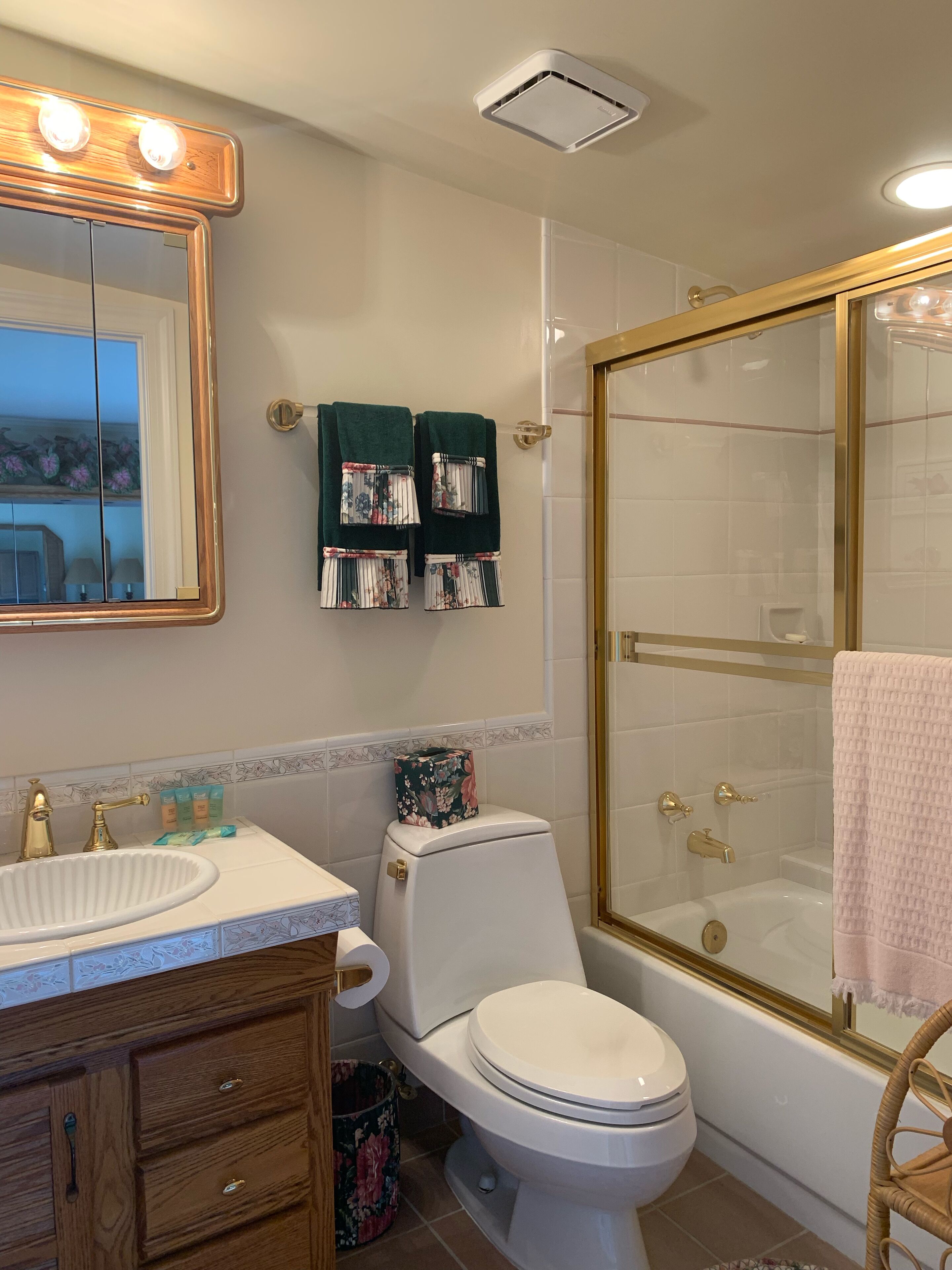 A bathroom with a white sink, a toilet, a shower with a glass door, and a mirror with lights.