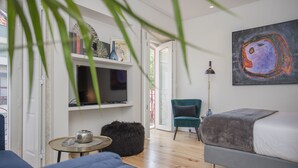 A modern living room with a sofa, a television, a bookshelf, and a painting. - Liiiving in Porto - Cozy & Chic Downtown (Porto)