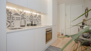 A modern kitchen with white cabinetry, a stainless steel sink, and a built-in oven. - Liiiving in Porto - Cozy & Chic Downtown (Porto)