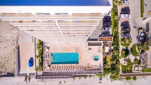 Vue aérienne d’un complexe hôtelier doté d’une piscine, d’une plage et de nombreux espaces de stationnement.