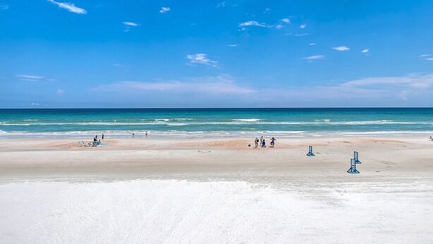 Une plage avec un ciel dégagé et une mer calme.