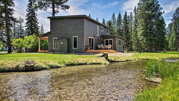 A modern two-story house with a deck, surrounded by a natural landscape with a small stream. - Creekfront Lincoln Home, Steps from Downtown! (Lincoln)
