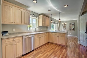 A spacious kitchen with wooden cabinets, stainless steel appliances, and a herringbone wood floor.