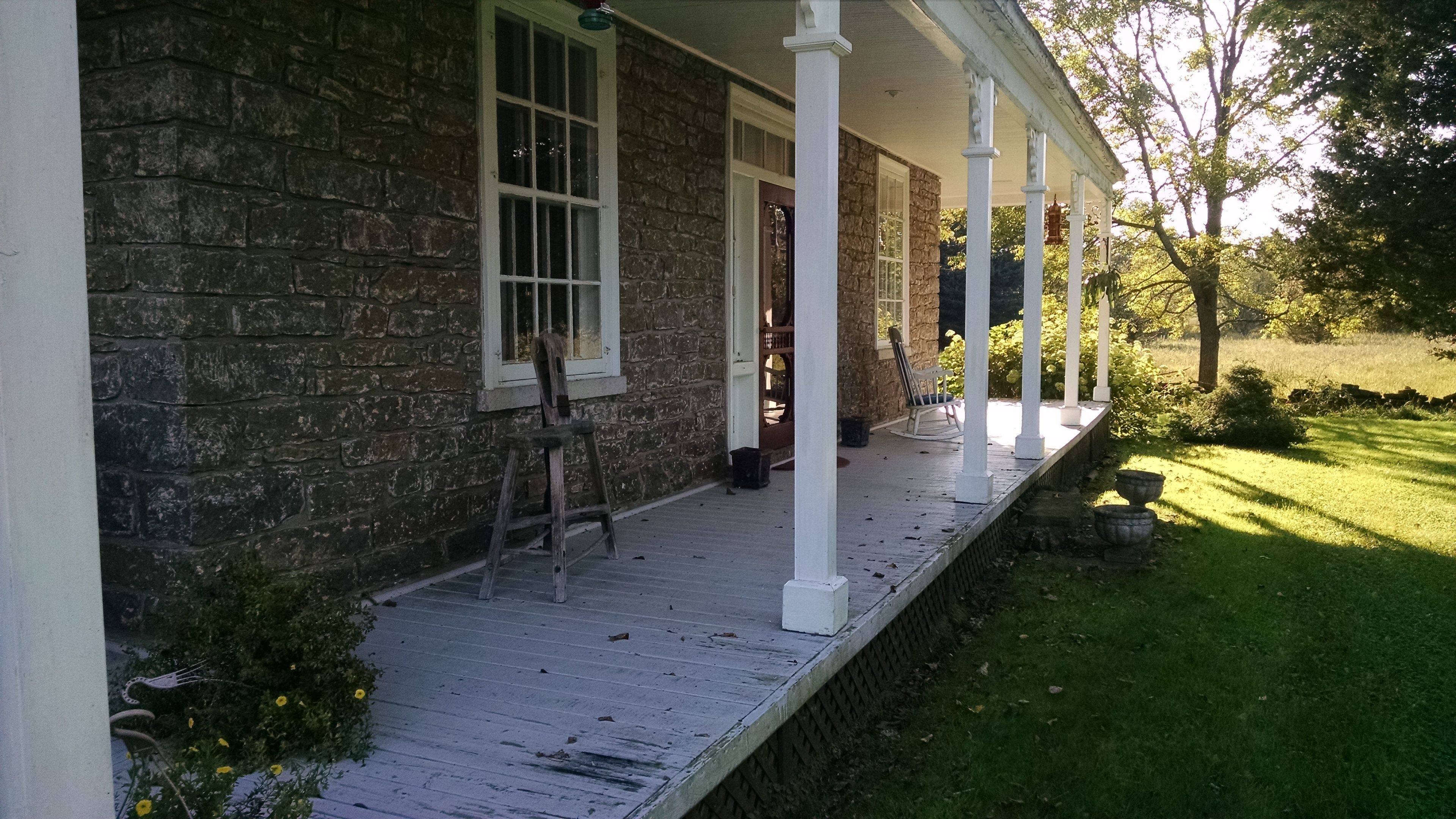A stone house with a wooden porch and a ladder leaning against it.